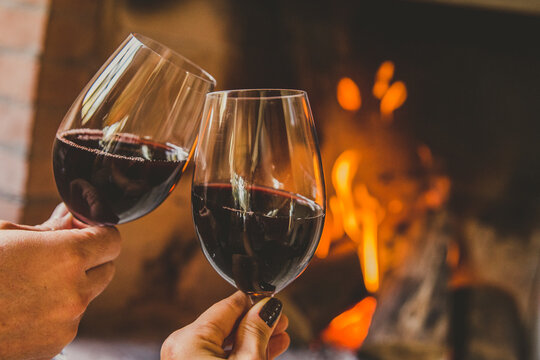 Casal brindando com vinho tinto em lareira no inverno