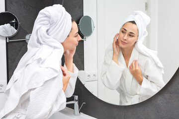 Content woman applying cream in light bathroom