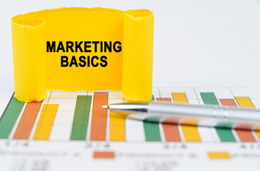 On the business charts are a pen and a paper plate with the inscription - MARKETING BASICS