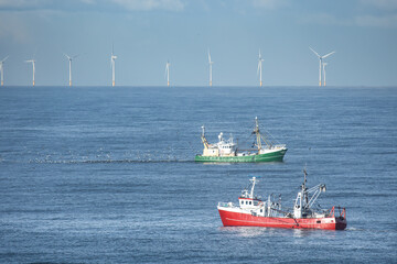 Two cutters passing each other in the North sea close with wind turbines of a windfarm in the...