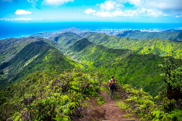 hiker girl enjoys the panorama of oahu island and honolulu in hawaii islands while climbing wiliwilinui ridge trail; hiking on green mountains in hawaii, holidays in hawaii