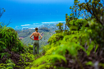 Naklejka premium hiker girl enjoys the panorama of oahu island and honolulu in hawaii islands while climbing wiliwilinui ridge trail; hiking on green mountains in hawaii, holidays in hawaii
