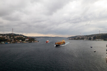 Fototapeta na wymiar Tanker, cargo ship passes through the Bosporus. Awesome view of the Bosphorus Bridge (the 15 July Martyrs Bridge) connecting Europe to Asia.