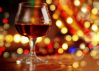 Foto op Plexiglas elegant glass of brandy on an expensive mahogany wood table, off-center, christmas lights, bokeh background. © Nokhoog