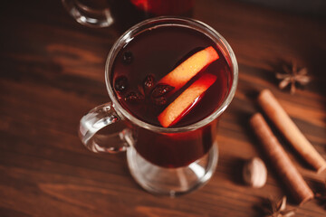 Mulled red wine in a glass and spices on wooden background