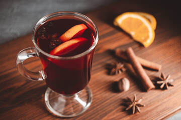 Mulled red wine in a glass and spices on wooden background