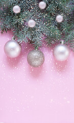 Fototapeta premium Christmas and New Year festive composition with snow fir tree branches, and gentle pink Christmas balls on the pink background