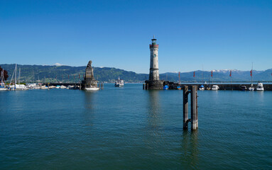 the beautiful sun-drenched harbour of Lindau island with beacon and the sculpture of the Bavarian Lion on lake Constance (Bodensee) with the Alps in the background, Germany on fine sunny spring day