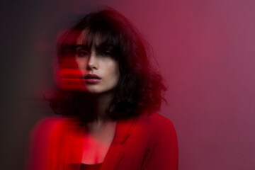 Portrait of woman with makeup and hairstyle, wear red suit, with closed eyes, red studio light and effects.