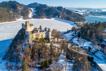 Poland. Medieval castle in Niedzica, dating back to 14th century (upper castle) in winter. Frozen artificial Czorsztyn lake on Dunajec river and a dam - 546977855