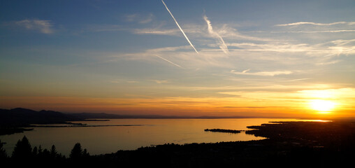 sunlit alpine view from Eichenberg in the Austrian Alps and the German side of lake Constance with island of Lindau in the evening sun in spring	
