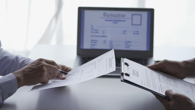 
A hiring manager interviews a woman at a job interview to discuss a resume. of young man giving resume or cover letter to human resources manager during job interview in office