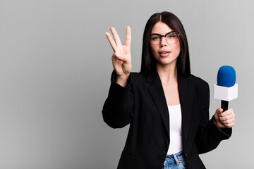 smiling and looking friendly, showing number three. journalist or presenter with a micro
