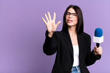 smiling and looking friendly, showing number five. journalist or presenter with a micro