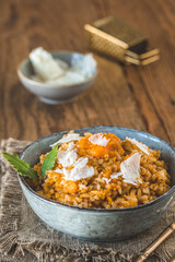 Homemade pumpkin risotto with parmesan cheese on a rustic wooden table