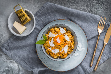Homemade pumpkin risotto with parmesan cheese on a gray concrete background
