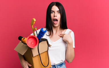looking shocked and surprised with mouth wide open, pointing to self. housekeeper with a toolbox