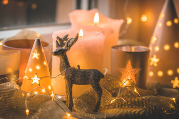 Christmas decorations in a window with glitter reindeer and various candles and glasses
