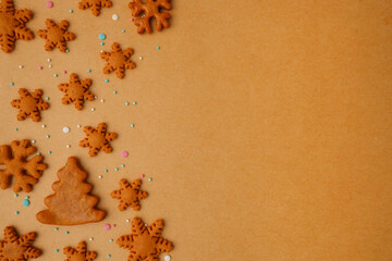 Christmas background of ginger cookies in the form of snowflakes and Christmas trees on kraft paper.Happy eco-friendly Christmas, preparation for Christmas Eve, a recipe for holiday cookies.Copyspace