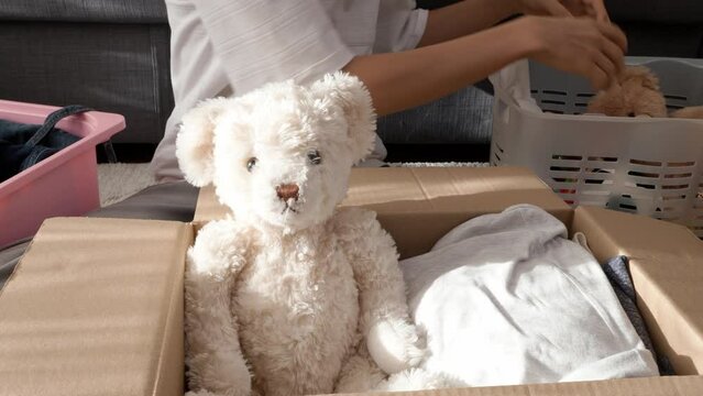 Boy preparing clothes and toys for charity donation. Teenage boy sorting and collect kid toys, clothes into boxes at home