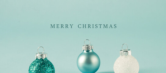 Merry Christmas text greeting with blue ornaments and background for holiday banner.
