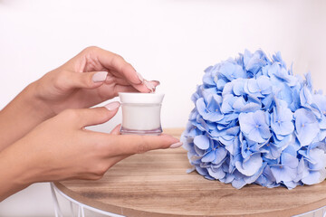 woman hands holds jar of cosmetic product mockup and flower on white background