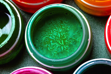 Beautiful, bright, mother-of-pearl, multicolored open cans of paint on a blue background. View from...