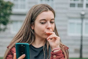 girl in the street with mobile phone and expression of suspicion or mistrust