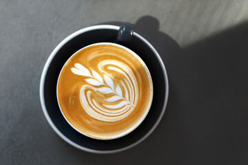 Aromatic cup of cappuccino with coffee art on a table in a cafe, top view