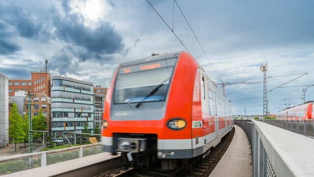 Moving train under the cloudy sky, surrounded by buildings, RMV, Deutsche Bahn in Frankfurt, Germany