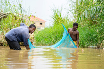 image of african people holding a net in a river- excited black guys fishing in a stream- fishing...