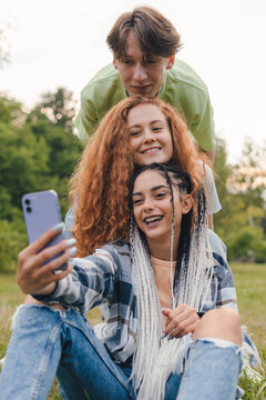 Group of diverse millennials people recording a video or taking a photo for social media. Young people having fun with new technology. Content creator concept