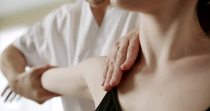 Physiotherapist treating wrist, shoulder and back of patient examined in hospital, Healthcare Concept in the professional clinic