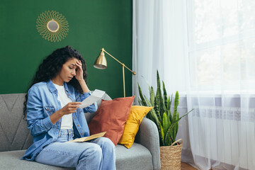 A young Latin American woman received divorce papers. Sitting at home on the rug, holding a sheet...