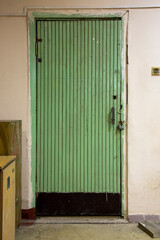 An old green door upholstered with wooden slats