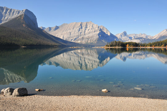 clear lake in the mountains creates mirror reflection image in Upper Kananaskis lake, Alberta, Canada