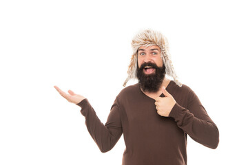amazed man point finger on copy space. mature man with beard in earflap hat.