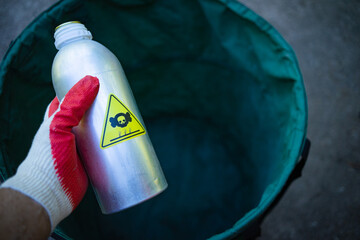 Disposal of toxic contaminated waste. A gloved hand throws out a metal bottle with an infected...