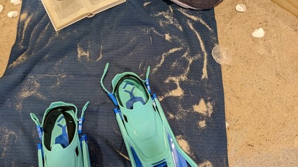 flippers with a book lies on a litter in the sand
