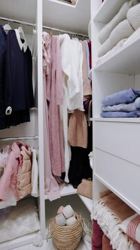 a walk-in wardrobe closet with apparels on hanger rails and shelves