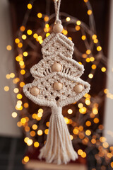 Christmas macrame toys on dark background. Natural materials - cotton thread, wood beads and stick. Eco decorations, ornaments, hand made decor. Winter and New Year holidays.
