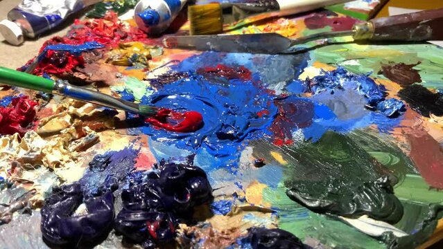 Palette with oil paints, brushes, palette knife. Drawing accessories. artist's workshop. mixes paints	
