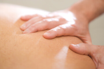 Massage Therapist Practitioner applies pressure with his hands on the back of his male patient.