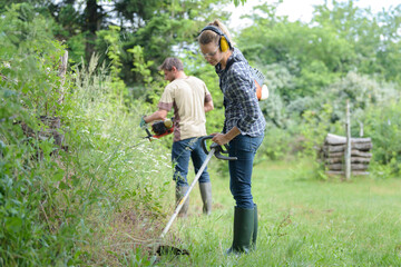 two people mowing the grass