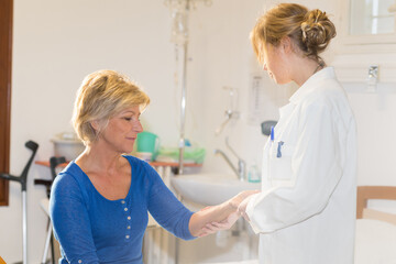 doctor examining senior female patients arm in hospital room