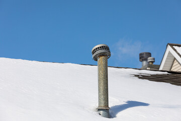 Snow drift on roof around furnace exhaust flue after winter storm. Heating safety, snow removal,...