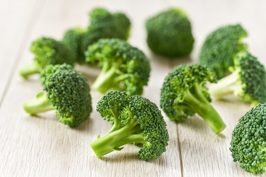 Fresh raw broccoli florets on a white cuisine table.