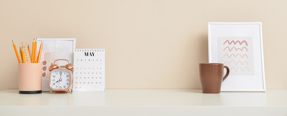 Alarm clock with stationery, calendar, pictures and cup at workplace in office