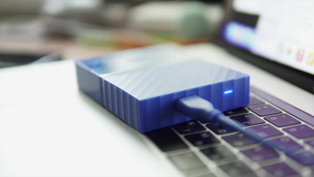 External HDD storage device connected to laptop, status white led lamp glows.