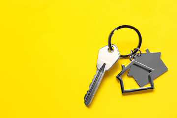 Key with house shaped keychain on yellow background